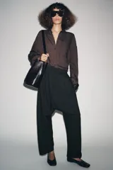 Pantalón baggy de tiro bajo confeccionado en mezcla de viscosa, con cintura elástica ajustable mediante cordones y detalle de pinzas en el delantero.