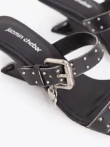 Sandalias de cuero vacuno efecto gastado color negro, con taco de 4 cm, tiras con mini tachas, hebilla metálica y dijes colgantes.