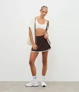 Short pollera deportivo de microfibra, color marrón con borde inferior contrastante en color blanco. Presenta un diseño ajustado y funcional, ideal para actividades físicas.