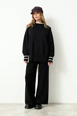 Sweater oversize de tejido rib color negro, con cuello redondo, mangas largas y puños con detalle de rayas en color beige.