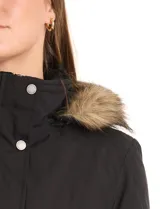 Gabardina impermeable de corte largo, color negro, con capucha desmontable con borde de piel sintética. Presenta cierre frontal oculto con botones a presión, cintura ajustable con jareta interna, bolsillos delanteros con solapa y detalle de costuras matelassé en hombros y bolsillos.