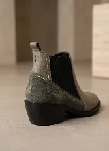 Bota tipo Chelsea de cuero negro con paneles laterales elásticos y taco bajo cuadrado. Presenta una combinación de texturas en el cuero y una presilla trasera para facilitar el calce.