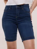 Bermuda de jean azul oscuro con calce ajustado y tecnología push up. Presenta cintura con presillas, cierre frontal con botón metálico, diseño clásico de cinco bolsillos y largo por encima de la rodilla con dobladillo en el ruedo.