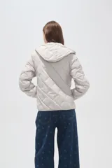 Campera acolchada de color beige con diseño capitoneado en forma de rombos, cierre frontal completo y capucha integrada.