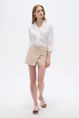 Short pollera color rosa viejo, de diseño cruzado tipo envolvente con detalle de botones laterales.