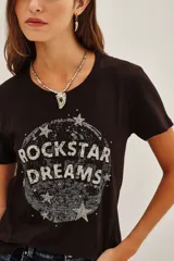 Remera de algodón color negro con estampa frontal circular que incluye la frase 'Rockstar Dreams' y estrellas decorativas.