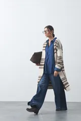 Cardigan largo de tejido de punto con diseño de rayas horizontales en tonos beige, marrón y blanco. Presenta una silueta relajada, mangas largas y frente abierto.