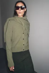 Chaqueta de tejido de punto color verde musgo, de corte cropped, con cuello redondo y cierre frontal de botones oscuros.