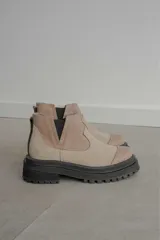 Bota tipo chelsea de punta redonda, confeccionada en una combinación de cuero texturizado y gamuza en tonos marrones. Presenta elásticos laterales negros y una suela track robusta de goma negra.