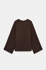 Blusa de viscosa color marrón oscuro, con cuello redondo y manga larga ancha estilo evasé. Presenta un corte recto y cierre de cremallera oculta en la espalda.