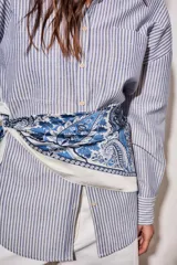 Camisa de corte oversize con diseño de rayas verticales en tonos azul y blanco. Presenta cuello clásico, cierre frontal con botones y mangas largas con puños abotonados.