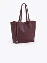 Cartera tipo shopper de cuero vacuno flor graneado, con formato amplio y estructura flexible. Presenta dos cierres verticales decorativos en el frente con tiracierres personalizados y doble manija de hombro.