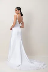 Vestido largo de novia blanco con corte imperio y tirantes finos. Presenta el cuerpo superior bordado a mano con abalorios y pedrería, faja drapeada con lazo lateral y falda fluida con cola.