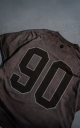 Remera manga corta de calce oversize en color chocolate con efecto batik. Presenta un estampado numérico '90' en la espalda y cuello redondo.
