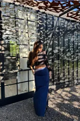 Falda larga azul de tafeta, ajustada en la cintura y con volado amplio con tajo lateral.