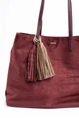 Bolso tipo tote de gran tamaño en color bordó, confeccionado en material con textura similar a la gamuza. Cuenta con doble asa larga para llevar al hombro y una pequeña placa metálica decorativa en el frente.