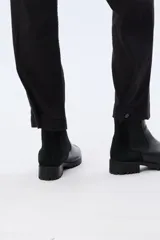 Pantalón de gabardina marrón, de corte recto con pinza en el bajo y detalles de botones en los tobillos.