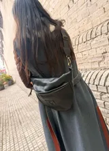 Riñonera de tamaño XL en color marrón chocolate, con diseño exterior trenzado y un parche frontal con monograma grabado. Cuenta con cierre diagonal y correa regulable.