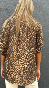 Camisa de manga corta con estampado animal print, cuello clásico y cierre frontal con botones. Presenta un corte holgado y fluido.