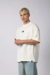 Remera de corte oversize confeccionada en algodón pesado, color negro. Presenta un bordado minimalista en el centro del pecho con forma de ojo y un parche estampado en la espalda que ilustra una mano abriendo una persiana.