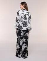 Conjunto de camisa y pantalón amplio con caída fluida. Camisa con escote en V y abotonadura frontal, mangas largas de corte caído con detalle de puntilla calada y puños elastizados fruncidos. Pantalón de tiro alto con cintura elastizada, pierna holgada de corte wide leg con dobladillo ancho en el ruedo y bolsillos laterales.