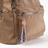 Mochila pequeña color beige con múltiples cierres plateados y colgante decorativo de cordones trenzados.
