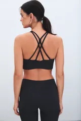 Top deportivo negro de escote redondo y espalda estilo nadadora, con banda elástica inferior para mayor soporte.