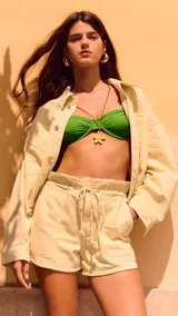 Chaqueta casual color amarillo pastel, de corte corto y suelto. Tiene cuello camisero, cierre frontal con botones metálicos, mangas largas y grandes bolsillos de parche en la parte delantera.