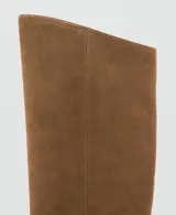 Bota de caña alta confeccionada en piel de serraje color marrón, con diseño flat, punta cuadrada y sin cierre.
