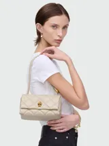 Bolso de hombro pequeño de cuero acolchado color beige claro, con diseño de rombos y cierre giratorio metálico dorado. Posee correa fina para llevar al hombro.
