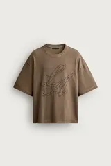 Remera relaxed fit color marrón con cuello redondo, manga corta y parche bordado a tono con letras en el frente.