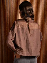 Campera corta de tela fina con diseño de paneles combinados, cuello camisero, cierre frontal con botones dorados y costuras a contratono.