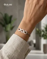 Pulsera de cadena fina de acero con dos dijes en forma de símbolo de infinito realizados en cerámica blanca.