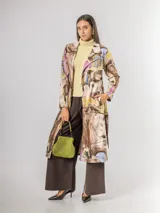 Trench de diseño urbano con acabado agamuzado, de corte recto y largo midi. Presenta un estampado abstracto multicolor con tonos rojizos, azules y ocres, cuello solapa, mangas largas y cinturón ajustable en la cintura.