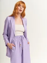 Blazer oversized lila de corte recto, largo a la cadera, con hombreras finas forradas, costuras internas con sesgo combinado y maxi bolsillos delanteros. Incluye lazo de algodón con detalle a tono.