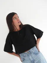 Top de punto negro con mangas cortas abuchonadas y bordado frontal sutil.