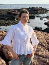 Camisa blanca de poplin de algodón con alforzas verticales y cuello alto estructurado. Mangas 3/4 con detalle de pliegues.