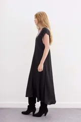 Vestido largo de viscosa jacquard, color negro, con escote en V y mangas cortas. Presenta detalles de ojalillos metálicos decorativos en el escote y en los bordes de las mangas.