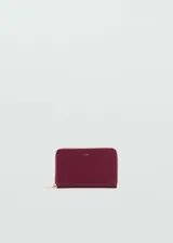 Billetera de tamaño mediano con efecto saffiano, cierre de cremallera perimetral y logo de la marca en relieve en la parte frontal. Cuenta con múltiples ranuras para tarjetas y un bolsillo interior con cierre.