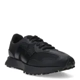 Championes urbanos New Balance modelo 327, color negro, confeccionados en una combinación de malla y material sintético. Presentan el logo 'N' característico en el lateral, cordones al tono y una suela de goma con relieve que se extiende hacia el talón.