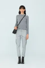 Sweater gris de punto con calce al cuerpo, volado en el ruedo y botones decorativos en el hombro.