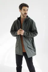 Campera impermeable verde con capucha, cierre frontal con botones a presión y bolsillos laterales con solapa.