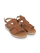 Sandalias de cuero color camel con tiras cruzadas, tira ajustable al tobillo con hebilla metálica y suela dentada bicolor.