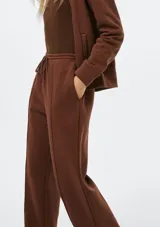 Pantalón de corte recto y holgado, color blanco, con cintura elástica y cordón ajustable. Presenta costuras verticales frontales que estilizan la silueta.