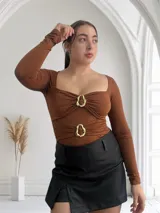 Body color marrón con escote cuadrado, mangas largas y detalle de hebillas doradas en el frente.