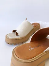 Sandalias de cuero crudo con tira ancha sobre los dedos y suela track color caramelo.