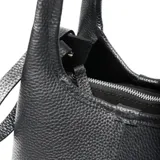 Cartera pequeña de cuero negro con textura granulada, diseño estructurado con doble asa superior y cierre mediante broche magnético. Incluye correa ajustable y extraíble, y cuenta con logo de la marca grabado en el frente.