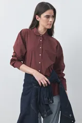Camisa de manga larga de algodón en color blanco, con cuello clásico, cierre frontal de botones y silueta relajada.
