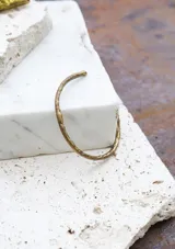 Pulsera rígida de bronce con textura irregular.