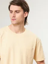 Remera de manga corta color arena, con cuello redondo y un bolsillo de parche en el pecho.